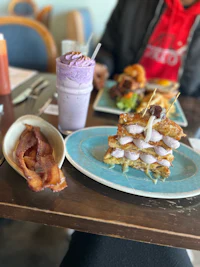 a plate of food with bacon and a drink on it