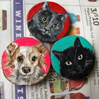 three painted wooden buttons with a cat and a dog on them