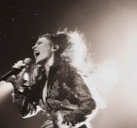 a black and white photo of a woman singing into a microphone