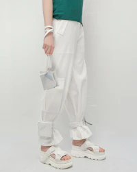 a woman wearing white pants and a green purse