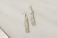 a pair of silver dangling earrings on a table