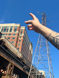 a person's hand reaching up to a power line
