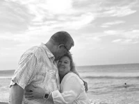 a black and white photo of a couple hugging on the beach
