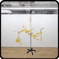 a yellow sculpture on a stand in an empty room
