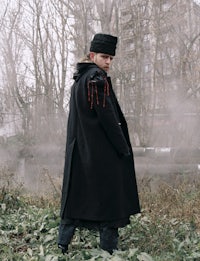 a man in a black coat standing in a field