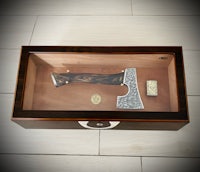 an axe is displayed in a wooden box