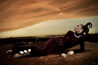 a woman in a red dress laying on the ground