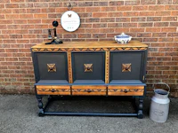 a painted wooden sideboard in front of a brick wall