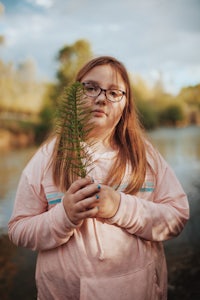 a girl holding a plant in front of a river