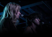 two women singing into microphones in a dark room
