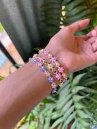 a woman's hand is holding a bracelet with flowers on it
