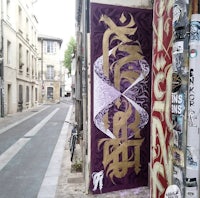 a purple and gold graffiti on the side of a street