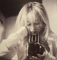 a black and white photo of a woman holding a camera