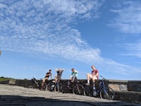 a group of people standing on a stone wall with their bicycles
