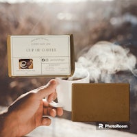 a hand holding a cup of coffee and a box of soap