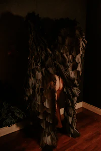 a woman dressed in black feathers standing in a room