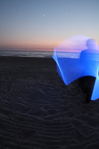 a person standing on a beach with a blue umbrella