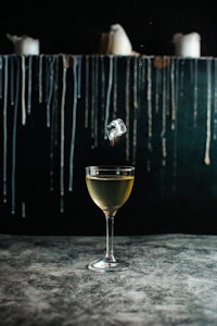 a martini is being poured into a glass on a table