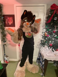 a mascot posing in front of a christmas tree