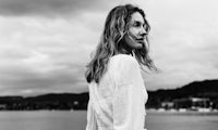 a black and white photo of a woman standing by the water