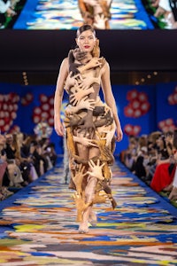 a model walks down the runway in a dress made of paper
