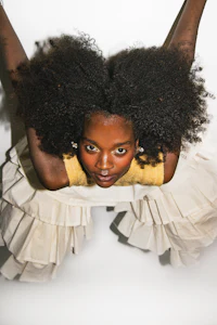 a woman with an afro posing in a white dress