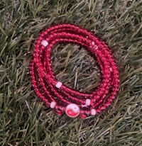 a red beaded bracelet sitting on the grass