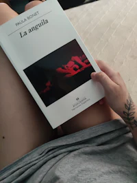 a woman holding a book with a tattoo on it