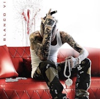 a man with tattoos sitting on a red couch