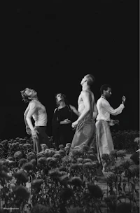 a black and white photo of a group of dancers in a field