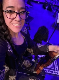 a woman in glasses is holding a violin
