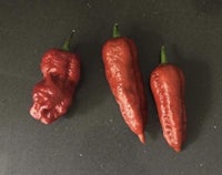 three red chili peppers on a black surface