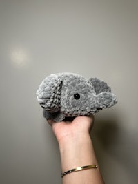 a person holding a grey elephant stuffed animal