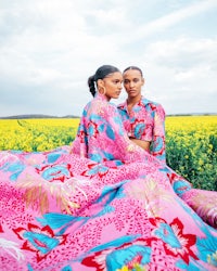 two women in pink dresses standing in a field