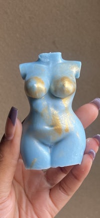 a person holding up a blue and gold body soap