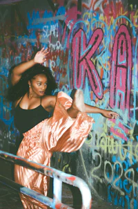 a woman doing a dance in a graffiti covered wall