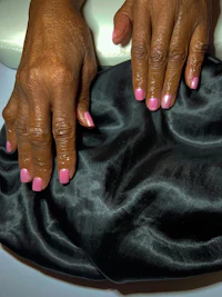 a woman with pink nails holding a black bag