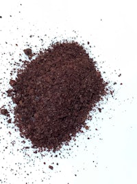 a pile of dark brown powder on a white surface