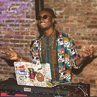 a man with a laptop in front of a brick wall