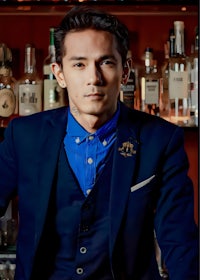 a man in a blue suit standing in front of a bar