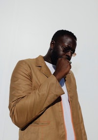 a man in a tan jacket smoking a cigarette