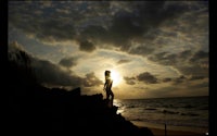 a silhouette of a person standing on a rock at sunset