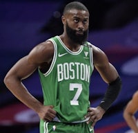 a boston celtics player with a beard standing on the court