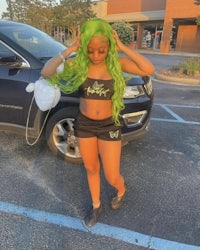 a woman with green hair standing in a parking lot