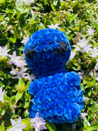a blue stuffed animal laying in the grass