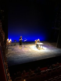two people sitting on a stage in a dark room