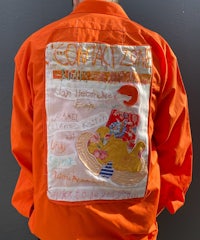a man wearing an orange jacket with writing on it