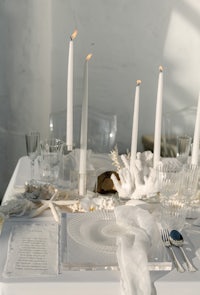 a white table setting with candles and seashells
