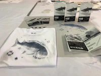 a white t - shirt with a fish on it is on a table