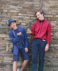 two boys leaning against a brick wall